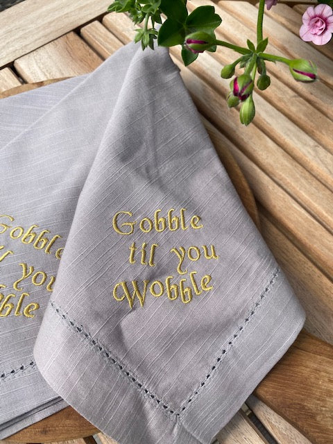 Servett i bomull med broderad text Gobble til you wobble, Grå, sälj 2-pack